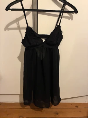 Svart spetsnattlinne med tunna band - Snyggt svart nattlinne med tunna axelband och spetsdetaljer upptill. 