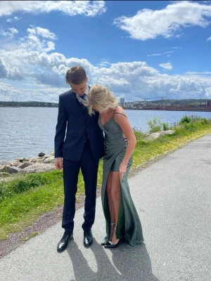 Grön balklänning med slits - Snygg grön långklänning i satin med hög slits och omlott-design. Klänningen har smala axelband, v-ringning och en elegant, figurnära passform. Perfekt för bal eller festliga tillfällen. Jag är 168 och har på mig 8 cm klackar så passar absolut längre oxå. Klänningen är i xxs men skulle säga att den passar mer som en xs. Ordinariepris 5200kr