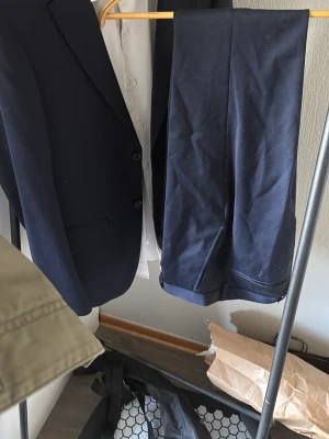 Mörkblå kostym med kavaj, skjorta och byxor, Dressmann - Snygg mörkblå kostym med klassisk kavaj och matchande byxor. Perfekt för finare tillfällen.