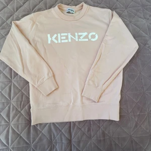 Beige sweatshirt från Kenzo - Säljer en beige sweatshirt från Kenzo med stor vit logga framtill. Den är knappt använd, bara att skriva vid frågor.💕💕