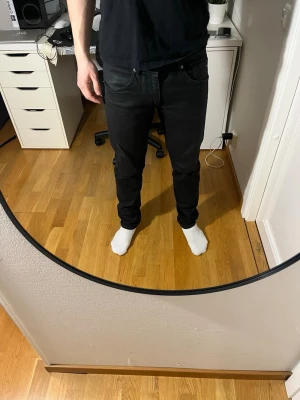 Svarta slim fit jeans från J.Lindberg - Säljer ett par svarta slim fit jeans från J.Lindberg med klassisk femficksdesign och knappgylf. Jeansen har en modern passform som sitter snyggt längs benen och passar perfekt till en avslappnad stil. Hör av dig vid frågor!