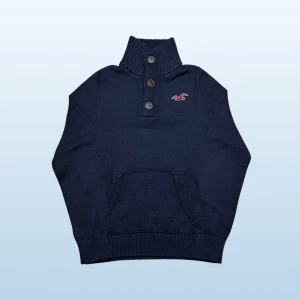 Vintage Hollister grovstickad 1/4 button up tröja - herr strl M  - Säljer en vintage Hollister 1/4 button up tröja i mörkmarinblå färg i storlek M med broderad Hollister logga på vänster sida av bröstkorgen.  👕 Märke: Hollister 📏 Storlek: M 🎨 Färg: Mörkmarinblå 🧵 Material: 56% bomull, 31% akryl, 13% polyester 📐 Mått: 70 cm lång, 50 cm bred 📌 Skick: Mycket bra skick (se bilder)  💬 Hör av dig vid frågor 💰 Pris kan diskuteras vid snabb affär 📦 Skickas inom 24 timmar