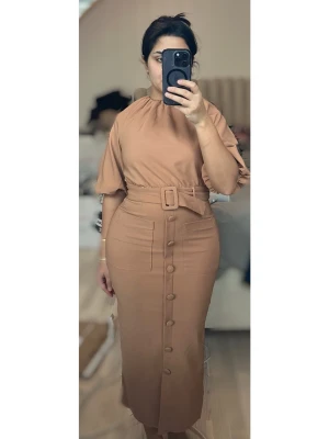 Klänning  med bälte - En beige/aprikosfärgad midiklänning med markerad midja och bälte. Klänningen har korta ärmar, knappar framtill och slits nedtill på båda sidor. Aldrig använd. 