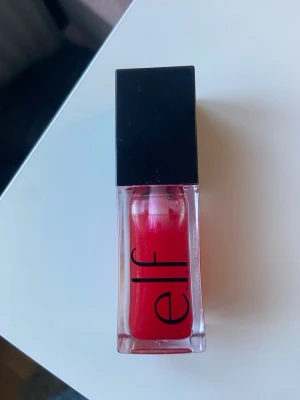 Rött läppglans från e.l.f. - Snyggt rött läppglans från e.l.f. i en stilren fyrkantig förpackning med svart lock. Glanset har en intensiv röd färg och ger en glansig finish. Perfekt för att ge läpparna en fräsch och färgstark look.