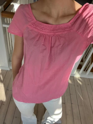 Rosa blus med spetsdetaljer - Söt rosa blus med korta ärmar och rund halsringning. Blusen har fina spetsdetaljer vid halsen och nederkanten. Perfekt för varma dagar och enkel att styla till jeans eller kjol 💗💗💗