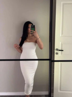 Vit bandeau långklänning - Säljer en vit bandeau klänning från Ginatricot. Har en lång pass form ner till vaderna. Använt 2-3 gånger oxh kommer inte till nån användning.