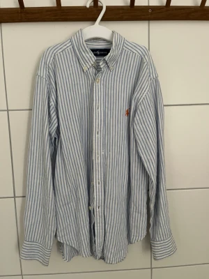 Blå&vit Randig skjorta från Ralph Lauren - Säljer nu min Ralph Lauren skjorta som är blå & vitrandig och har ett orange Ralp Lauren märke. Den är i ett mycket bra skick och är andvänd ett fåtal gånger. Vid andra frågor eller funderingar så är det bara att höra av sig.