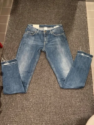 Blå jeans med råa kanter från Dondup - Snygga blå jeans från Dondup med klassisk femficksmodell och råa, fransiga benslut. Jeansen har en tvättad look och gul kontrastsöm. Perfekta för en avslappnad och trendig stil.