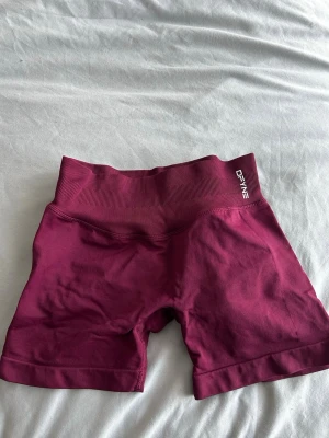 Winterberry shorts  DFYNE - Snygga winterberry träningstights-shorts från DFYNE med hög midja och ribbad linning. Tillverkade i ett stretchigt material som sitter tight och bekvämt. Perfekta för gymmet eller andra träningspass.