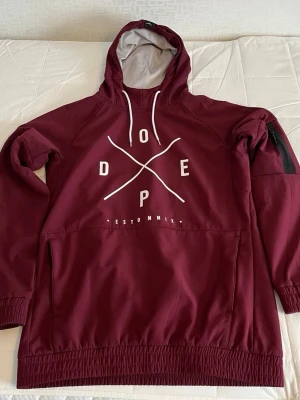 Vinröd hoodie från Dope - Snygg vinröd hoodie från Dope med stor vit logga på bröstet. Hoodien är perfekt för fjällen för en stilren och varm look. Skriv gärna vid minsta fundering! 🥰 Köpte för nypris: 1799 kr. 