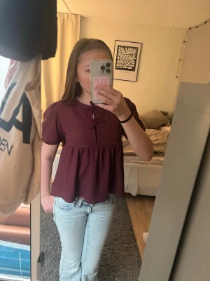 Vinröd blus med puffärmar - Säljer en vinröd blus med korta puffärmar och har en söt knytning framtill. Storlek 150 men passar S/XS ❤️