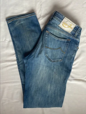 Jeans från Jacob Cohën 688 - Snygga blå jeans från Jacob med klassisk femficksdesign och guldfärgad logga på bakfickan. Jeansen har en slim fit-modell och coola slitningar framtill. Jeanes är W36 men upplevs som  W34 då det är slim fit modell. Modell 688. Hör av dig vid minsta fundering⁉️