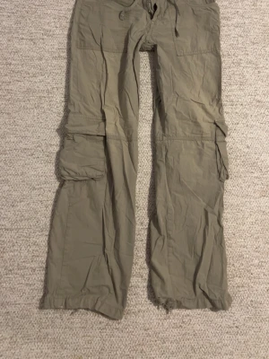 Gröna cargobyxor från Topshop - Snygga gröna cargobyxor från Topshop med dragsko i midjan och stora fickor på sidorna. Byxorna har raka ben och är tillverkade i ett lätt bomullsmaterial. Perfekta för en avslappnad och trendig stil.