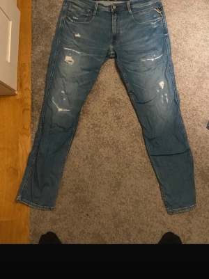 Blå slitna jeans med raka ben - Säljer ett par ljusblå jeans med raka ben och slitna detaljer framtill. Knappt använda