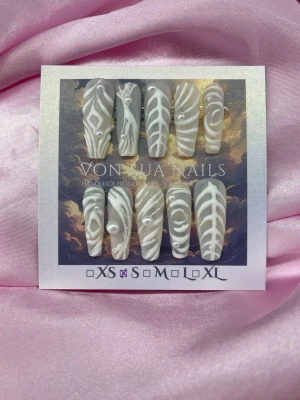 LowkeyLuxe (S);Long Ballerina  - Säljer ett set handgjorda press-on naglar i storlek S: 15 mm, 11,5 mm, 12 mm, 11 mm, 9 mm . Naglarna är vita med unika handmålade 3D-mönster och pärldetaljer. Formen är lång och ballerina. Perfekt för dig som vill ha något extra till naglarna!