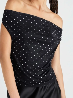 Svart offshoulder prickig topp - Trendig svart offshoulder topp med vita prickar och öppen rygg. Den går att bära antningen som modellen på bilden eller som en vanlig halterneck topp. Tillverkad i mjukt material som sitter snyggt mot kroppen. Perfekt för dig med en cool och trendig stil.🥰❤️Nytt skick!