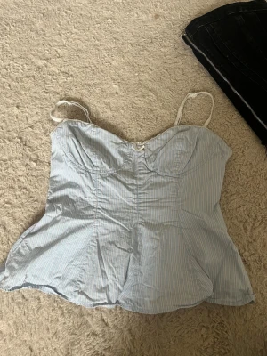 Ljusblå zara topp - Säljer denna super fina  ljusblåa toppen med tunna vita vertikala ränder och smala axelband. Toppen har en figurnära passform och markerade sömmar som ger en snygg siluett.💕