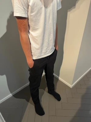 Svarta slim fit jeans - Snygga svarta slim fit jeans med klassisk femficksdesign och normal midja. Jeansen har raka ben och är tillverkade i ett stretchigt material som ger en bekväm passform. Perfekta för dig som gillar en stilren och enkel look. Modellen i bild är 184.