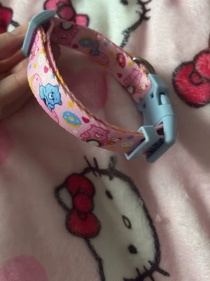 Pastellfärgat Care Bears halsband till Hund - Sött halsband till hund i tyg med Care Bears-motiv i pastellfärger på rosa botten. Spänne och justerare i ljusblå plast samt metallring för dekorationer eller nycklar. Liten hund ✨