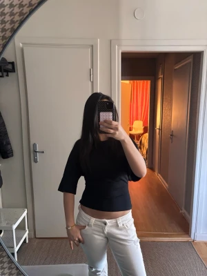 Svart croppad topp med knyt i ryggen - Trendig svart croppad topp med halvlånga ärmar och snygg knytning i ryggen som ger en öppen rygg-effekt. Den är använd fåtalgånger och har inga tecken på skador. Skriv gärna för mer information 💕