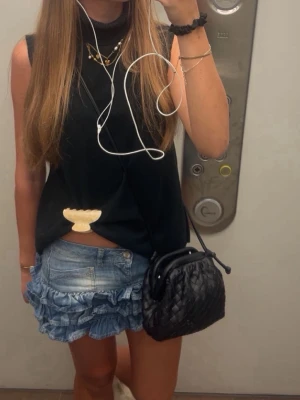 Blå jeanskjol med volanger - Supersöt kort jeanskjol i ljusblå denim med dubbla volanglager längst ner. Kjolen har en klassisk femficksdesign och en liten patch bak i midjan. Perfekt för dig som vill ha en trendig och lekfull look.