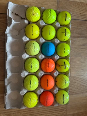 Färgglada golfbollar 18st - Säljer ett set med golfbollar i olika färger, inklusive gul, orange och blå. Bollarna är tvättade