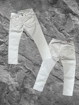 DONDUP JEANS - Säljer ett par vita jeans från Dondup slim/skinny passform och klassisk femficksdesign. Jeansen har den klassiska logan med siffror bak på dem. De är tyvär klippta på längden så jag skulle vilja säga att de passar dig som är 172-175, detta är bara ett ungefär om du vill vara säker kolla måtten. Perfkta inför sommaren med en skön stil.                   Midja: 42cm Benlängd: 85cm Lårbredd: 20,5cm