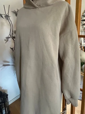 Beige oversized hoodie - Mysig oversized hoodie i beige med huva och långa ärmar. Hoodien har en enkel och stilren design utan tryck eller mönster, samt ribbade muddar vid ärmsluten. Perfekt för en avslappnad och trendig look. Materialet känns mjukt och skönt mot huden.
