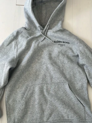 Björn Borg hoodie  - Grå, mjuk och skön hoodie från Björn Borg med ett svart tryck på vänstra bröstet