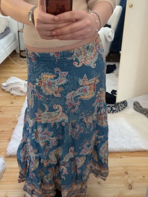 Blå långkjol med paisleymönster - Säljer en blå långkjol med färgglatt paisleymönster den är verkligen jättefin men känner att en inte riktigt är min stil längre! Priset är inte hugget i sten!🫰🏻🥰