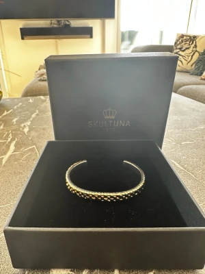 Skultuna Scale Cuff design Thomas Sandell - Silver plated - Snyggt silvrigt armband från Skultuna med tvinnad design och pärldetaljer. Öppet och stilrent, perfekt för dig som gillar klassiska accessoarer med en modern twist. Märkt med Skultuna och designerns signatur på insidan. Nypris: 1150kr 