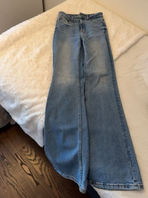 Blåa wide leg jeans från Zara - Säljer ett par ljusblå wide leg jeans från Zara med hög midja och klassisk femficksdesign. Jeansen har en snygg tvättad look och raka, extra vida ben som ger en trendig siluett. Perfekta för dig som gillar avslappnad och cool stil.