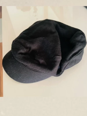 Keps/ skepparmössa - Keps/ seglarmössa i svart. Kepsen har ett justerbart spänne i metall baktill för passformen. Perfekt till ex. Höst/ vår outfits.