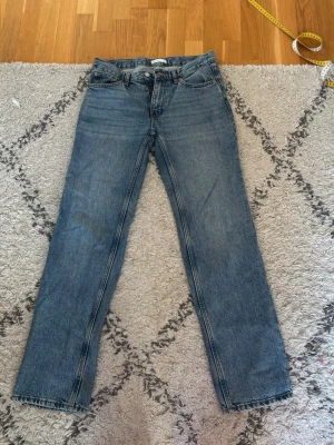 Lågmidjade blå raka jeans från Gina tricot - Klassiska blå jeans från Gina med rak passform och fem fickor. Jeansen har en snygg tvättad look, dragkedjegylf och bälteshällor. Tillverkade i slitstark denim som passar perfekt till en avslappnad stil.