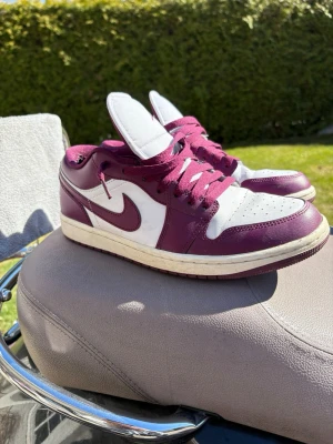 Nike Air Jordan 1 Low Bordeaux/Vit - Snygga Air Jordan 1 Low sneakers i bordeaux och vitt läder. Klassisk siluett med perforerad tåbox, vita paneler och bordeauxfärgade detaljer samt snörning. Ikonisk Swoosh på sidan och Jumpman-logga på plösen. Perfekta för dig som vill sticka ut med stil. Använda ett fåtal gånger. Pris kan diskuteras!