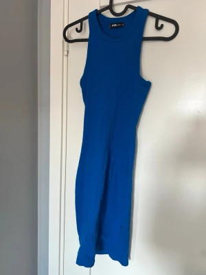Blå ärmlös ribbad klänning - Säljer en blå, ärmlös ribbad klänning. Klänningen har en kroppsnära passform och rund halsringning. Perfekt för dig som gillar enkel men snygg stil.