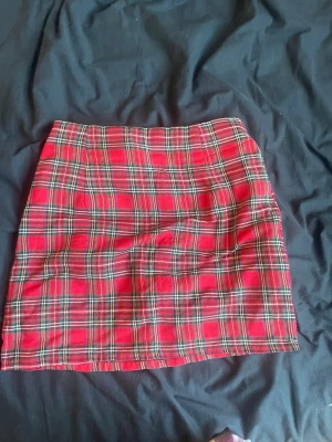 Rutig röd kortkjol i bomull - Säljer en snygg röd kortkjol med klassiskt rutigt mönster. Kjolen har en rak passform och är tillverkad i mjuk bomull, perfekt för att skapa en cool och trendig look. Passar perfekt till en enkel t-shirt eller stickad tröja.(klicka ej köp nu) kontakta gärna och Swish går 