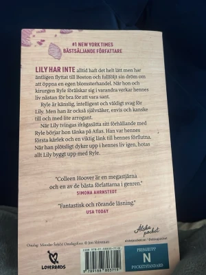 Det slutar med oss av Colleen Hoover - Säljer boken 'Det slutar med oss' av Colleen Hoover. Pocketbok med omslag i ljusrosa och lila, dekorerad med blommor och stora lila bokstäver. En gripande roman om kärlek, relationer och att våga börja om. Perfekt för dig som gillar starka berättelser.