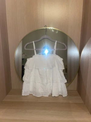 Vit volangig linnetopp med smala band - Söt vit linnetopp med tunna axelband och flera lager volanger i storlek 158-164 . Toppen har en luftig och flowy passform, perfekt för varma dagar. Materialet känns lätt och mjukt mot huden. Enkel att matcha med jeans eller kjol för en fräsch look.skriv för fler bilder, pris kan diskuteras!💗(inga defekter och är använd en gång)