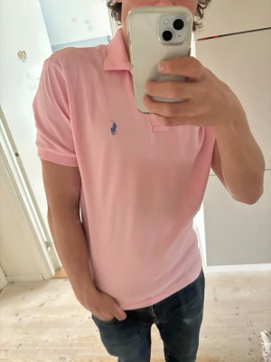 Ralph Lauren pike  - Hej! Säljer en rosa pikétröja från Ralph Lauren med blå broderad logga på bröstet. Perfekt för en stilren och avslappnad look. Storlek M. Hör av er vid frågor. 