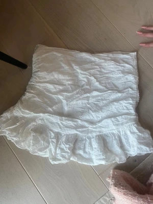 Vit kortkjol med volang och spets - Supersöt vit kortkjol med volangkant och broderad spetsdetalj. Går att ha både högmidjat eller vika ner så den sitter lågmidjat, skriv för fler bilder!!💕