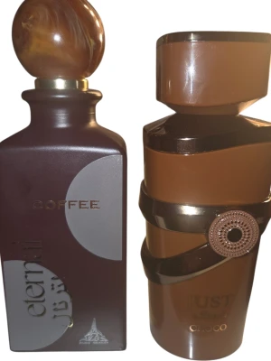 Två parfymer set - Två unika parfymflaskor i bruna nyanser. Den ena flaskan heter Eternal Coffee och har en marmorerad rund kork, medan den andra heter Just Oud Choco och har en asymmetrisk design med dekorativt band. Båda flaskorna är tillverkade i glas och har eleganta detaljer i guld.