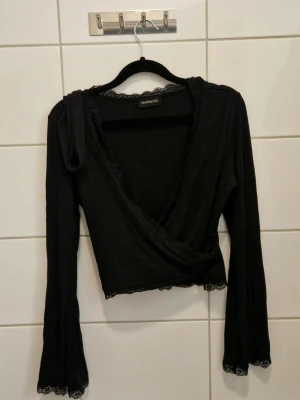 Svart topp i omlott - Använd en gång. Stretchigt material så passar de flesta. Spets vid kanterna och vida ärmar. 