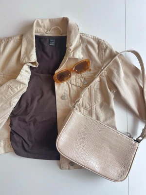 Y2K outfit bundle: brun baby tee + jeansjacka + beige väska + solglasögon - stl S - Y2K inspirerat outfit bundle beige/brun 🤎  Kit med 4 delar: • brun tight baby tee, stl s • beige jeansjacka, stl xs • beige/bruna solglasögon • beige axelväska i krokodilmönster  Perfekt Y2K-outfit för vår/sommar 🤎 Alla plagg i fint skick. Kolla gärna in mina andra kit 💌 Fler bilder finns!