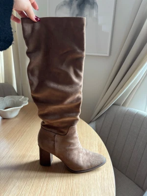 Bruna höga stövlar med klack - Säljer ett par snygga bruna stövlar i mockaimitation med hög, bred klack. Inga defekter alls!