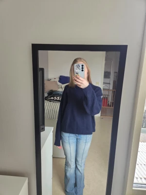 Mörkblå stickad tröja - Mysig mörkblå stickad tröja med oversized passform och långa ärmar. Tröjan har en enkel, klassisk design utan synliga mönster eller detaljer. Perfekt att matcha med jeans för en avslappnad look.