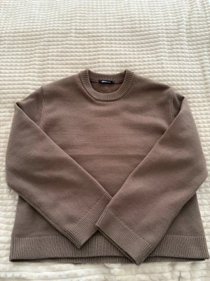 Brun stickad tröja från Ginatricot - Säljer en enkel och stilren brun stickad tröja från Ginatricot. Tröjan har rund halsringning, långa ärmar och ribbade muddar vid ärmslut och nederkant. Perfekt att matcha med jeans eller kjol för en avslappnad look.