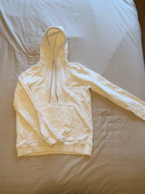 Vit dondup hoodie med broderad logga - Snygg vit hoodie från Juicy Couture med broderad D-logga på bröstet. Hoodien har en stor huva med dragsko och en klassisk magficka. Tillverkad i mjukt bomullsmaterial som är skönt mot huden. Perfekt för en avslappnad och trendig look.