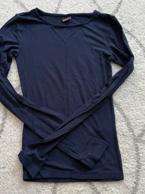 Marinblå topp - Marinblå tajt tröja från Gina i second skin material med slits i båda ärmarna.