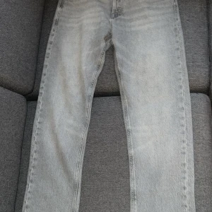 Ljusblå raka jeans - Säljer ett par ljusblå jeans med rak passform och klassisk femficksdesign. Jeansen har en tidlös tvätt och är tillverkade i denim. Perfekta för en avslappnad och trendig look.